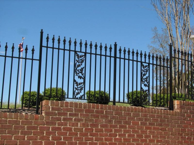 Black wrought iron fence with decorative panels on a brick wall