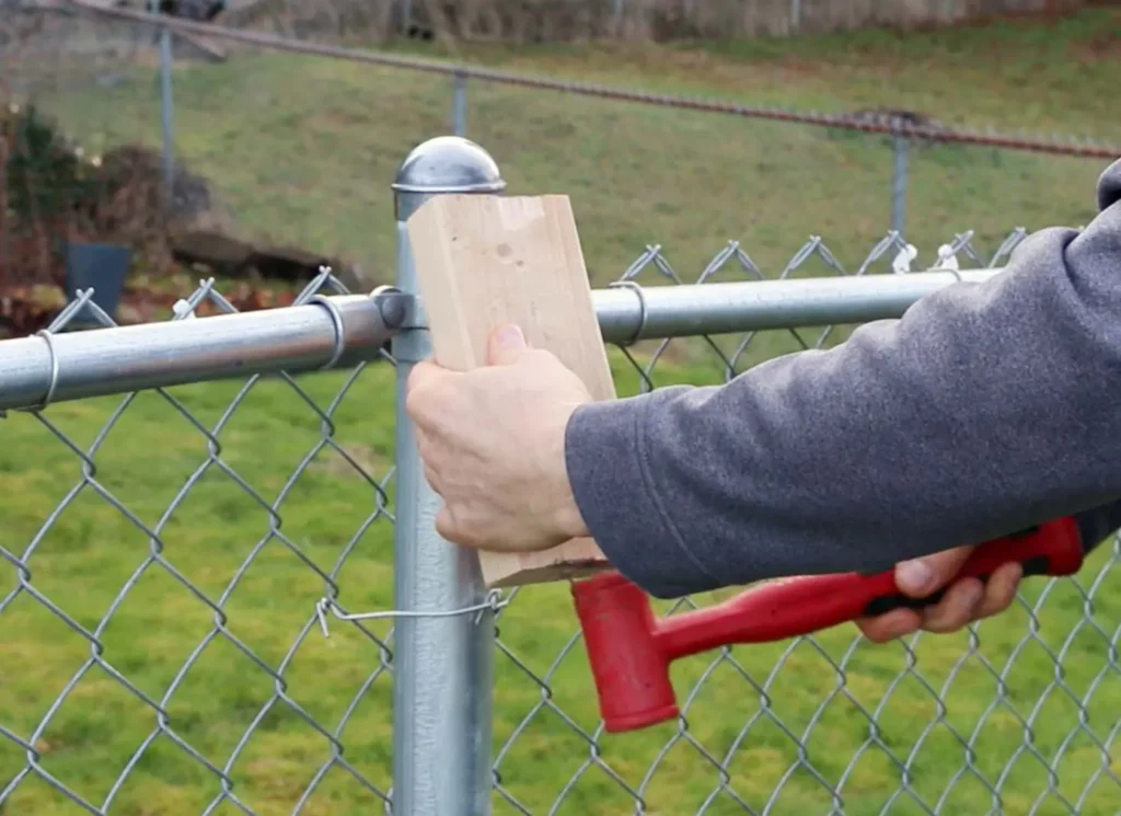 Installer tightening a chain link fence post fitting