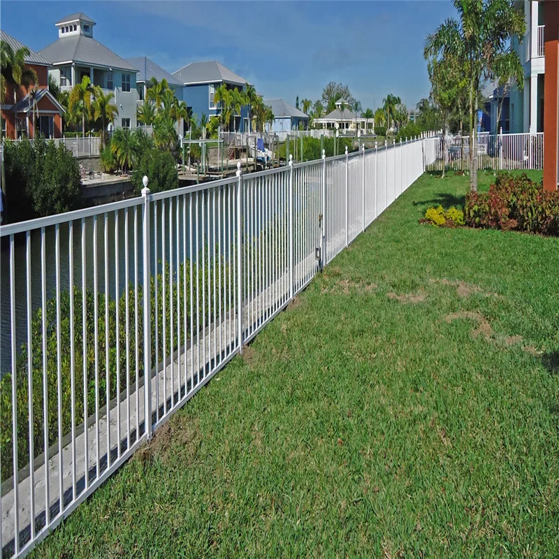 White aluminum picket fence along a sunny lawn