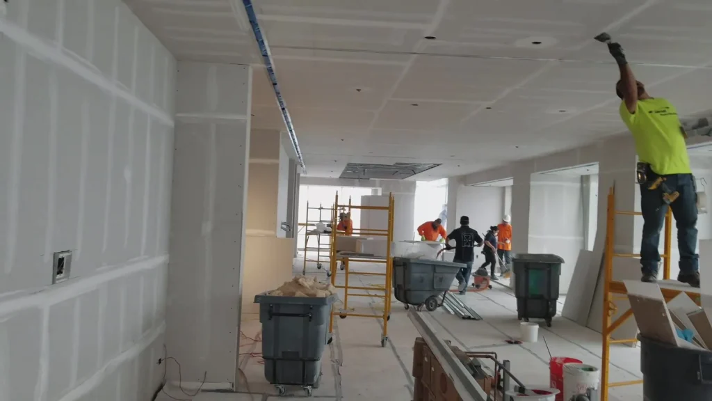 Crew finishing drywall in a large commercial space