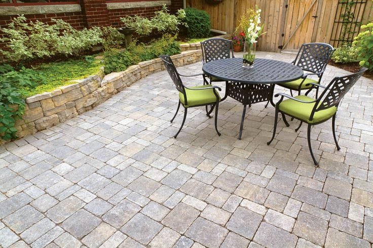 Paver patio with a wrought iron dining set and green cushions