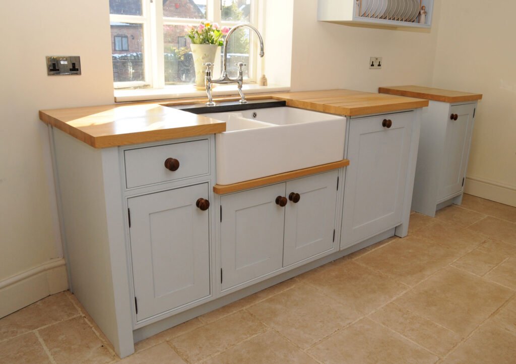 Light blue kitchen cabinets with a farmhouse sink and wood countertops