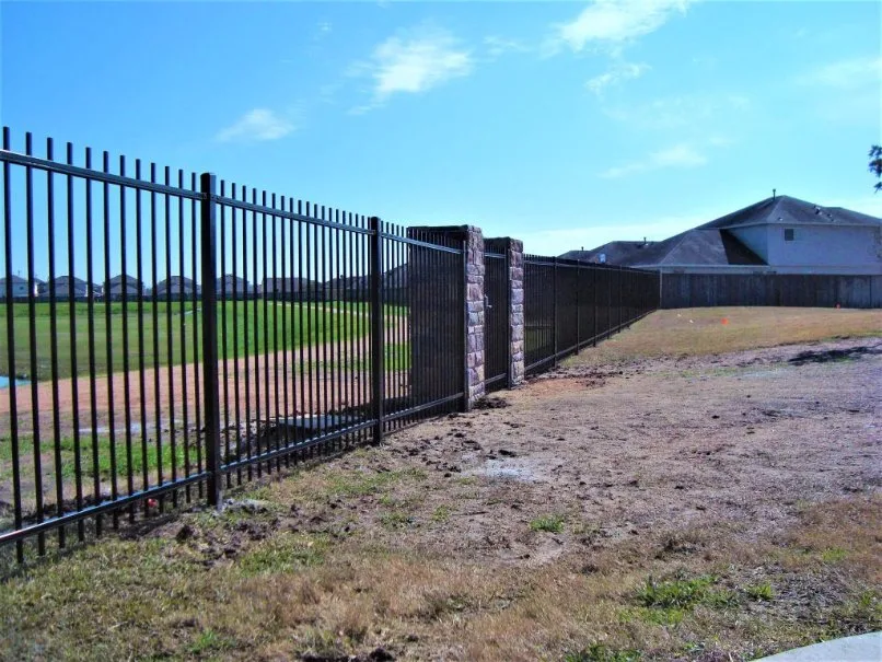 Black ornamental steel fence with stone pillars