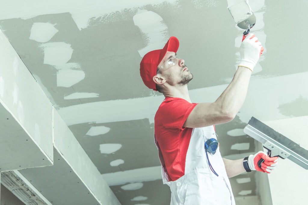 Drywall finisher applying compound to a ceiling joint
