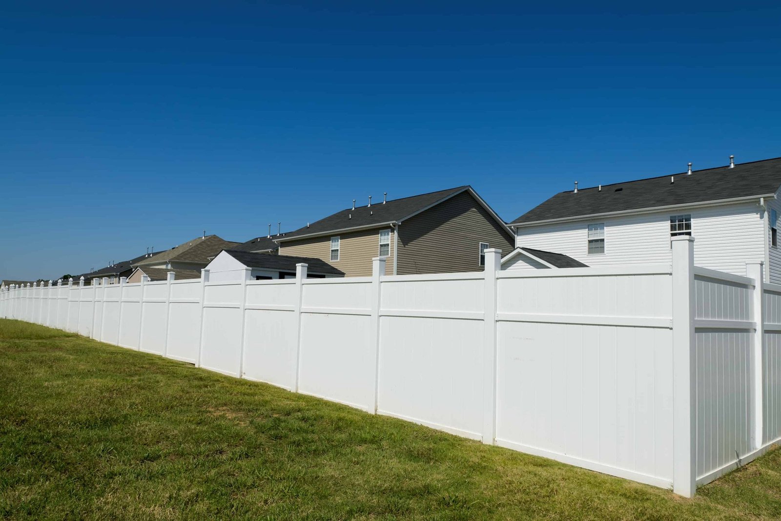 White vinyl privacy fence along a lawn