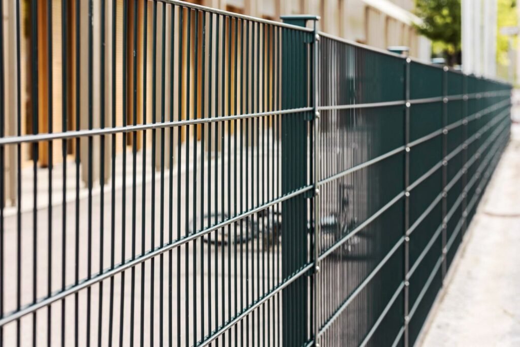Dark green welded-wire metal fence panels along a walkway
