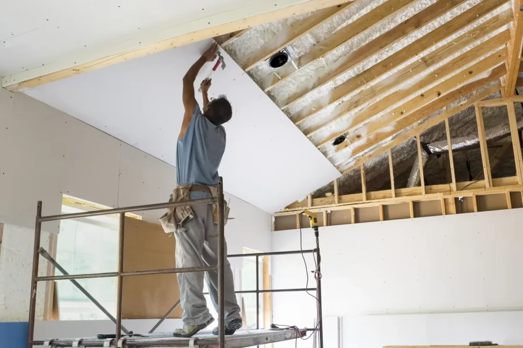 Contractor hanging drywall on a vaulted ceiling