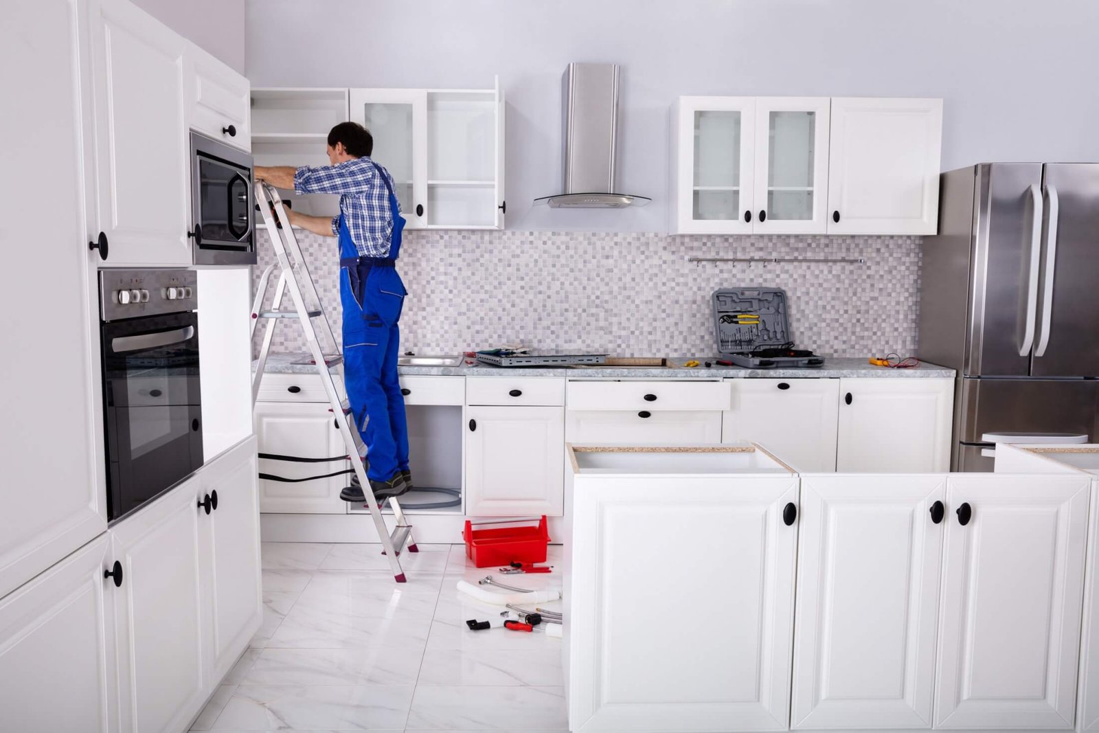 Handyman installing upper cabinets in a white kitchen