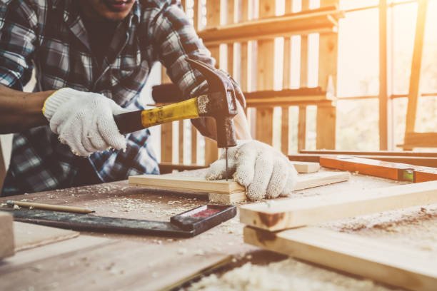 Carpenter hammering wood trim in a workshop