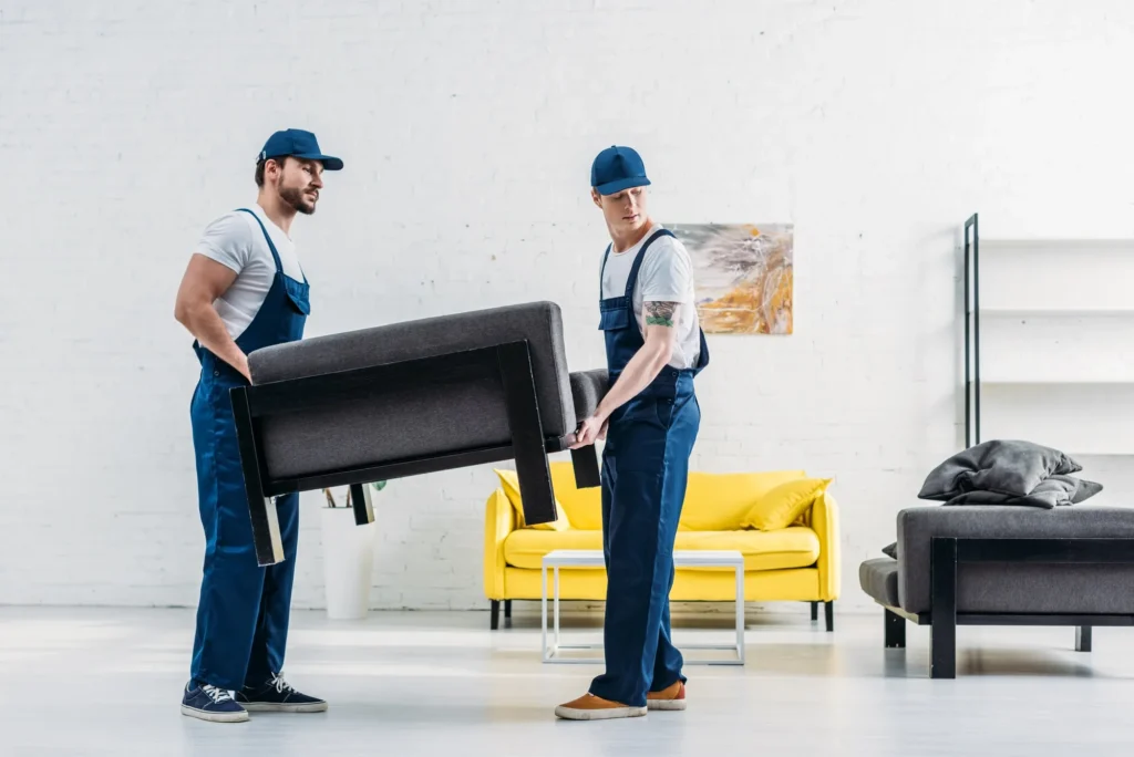 Two movers carrying a black sofa